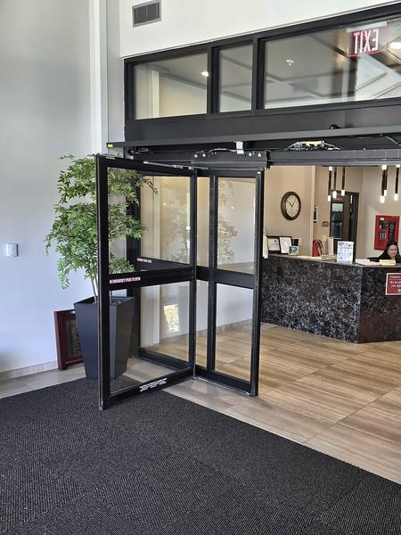 Open automatic aluminum-and-glass entrance doors with an overhead transom, leading into a lobby