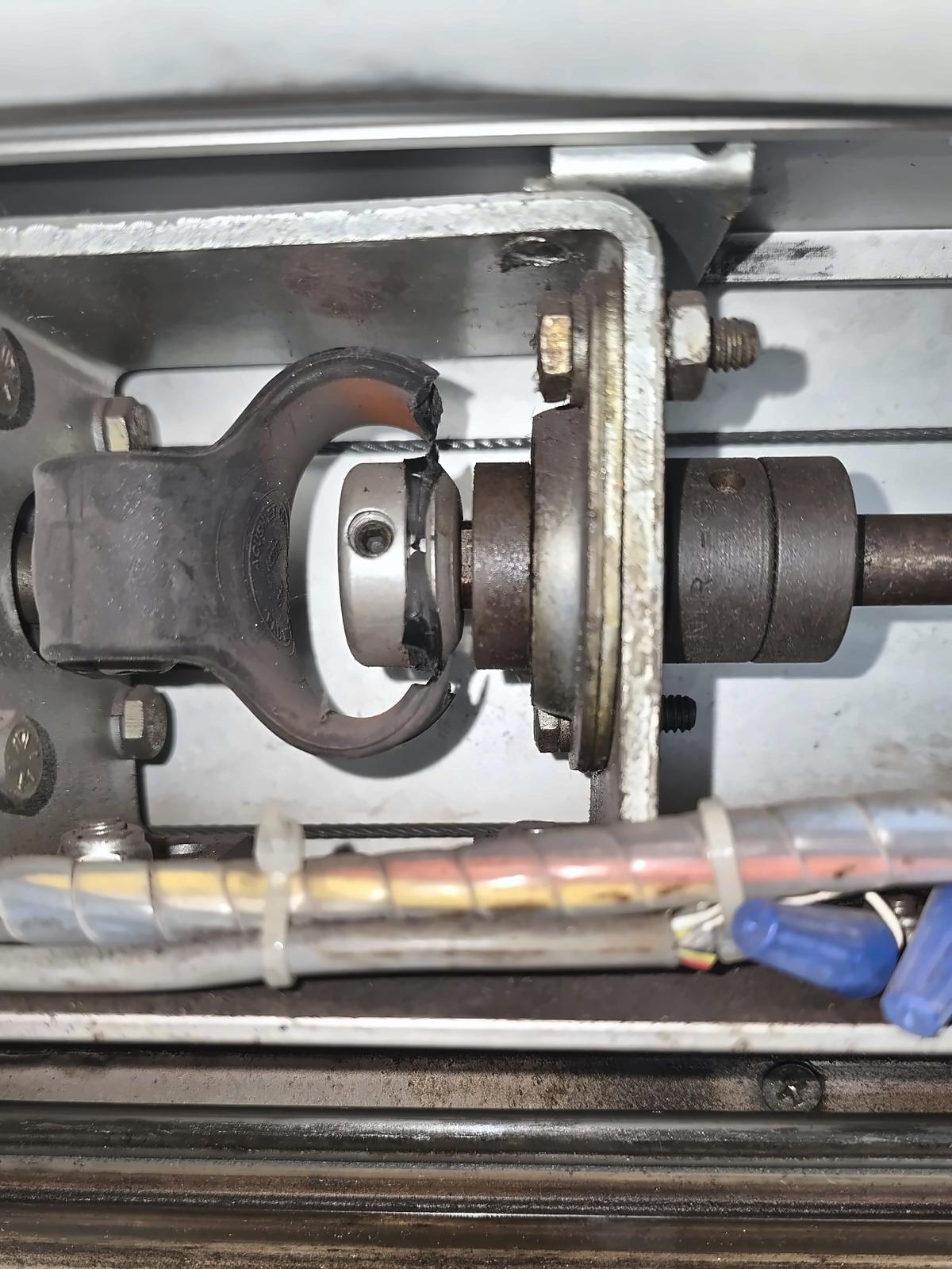 Close-up of an automatic sliding door operator drive coupling and shaft inside the header