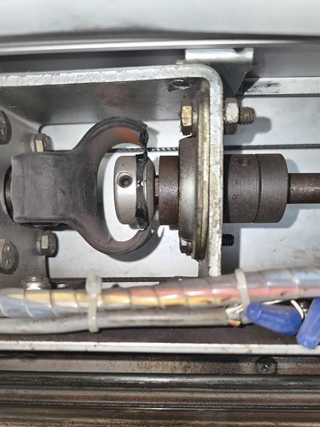 Close-up of an automatic sliding door operator drive coupling and shaft inside the header